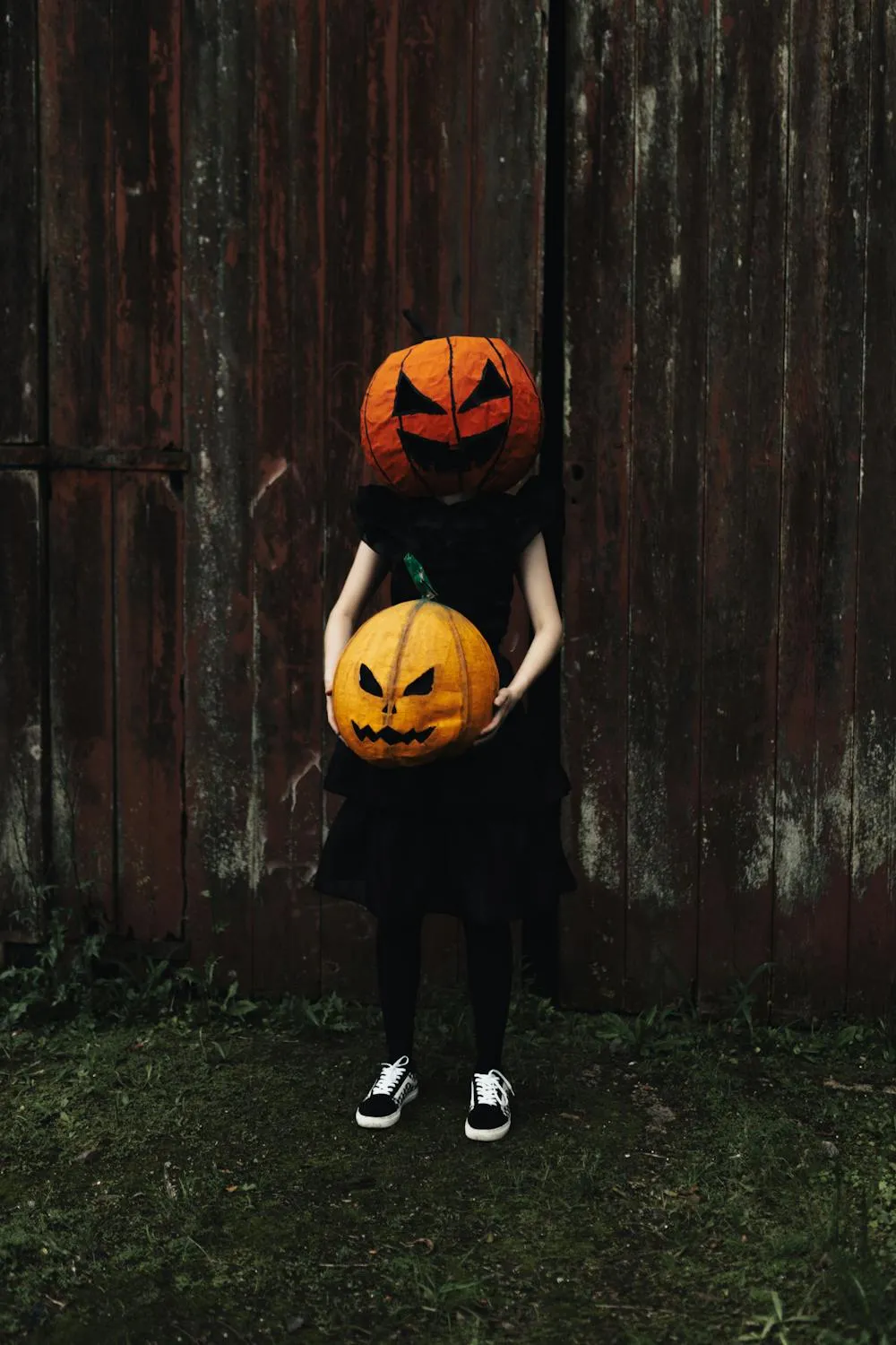 Child Holding Pumpkin Mask in Front of Fence Wallpaper