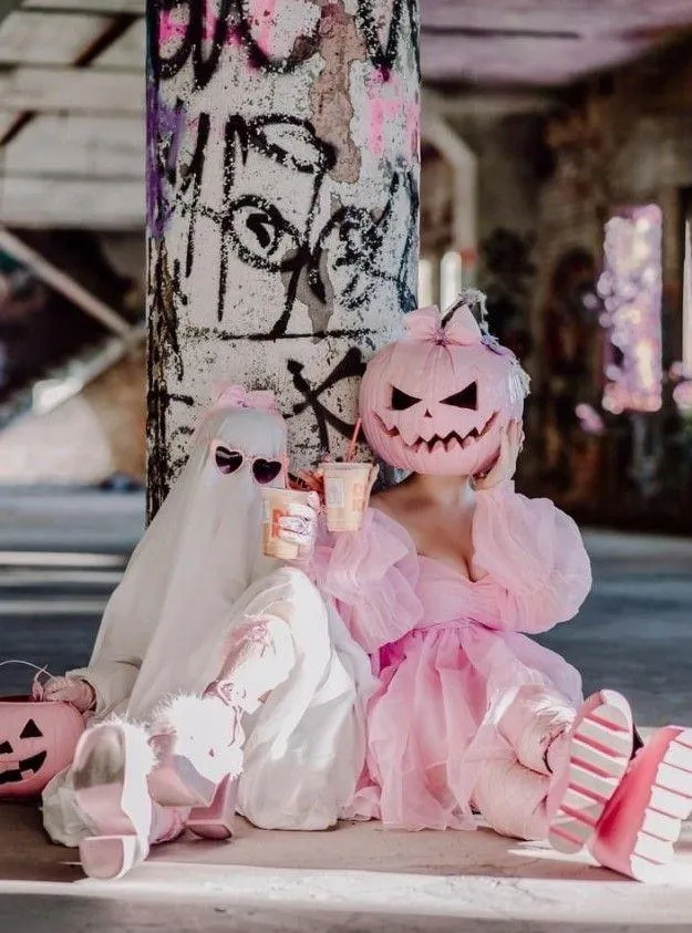 Child in Pink Costume with Pumpkin Head Holding Doll