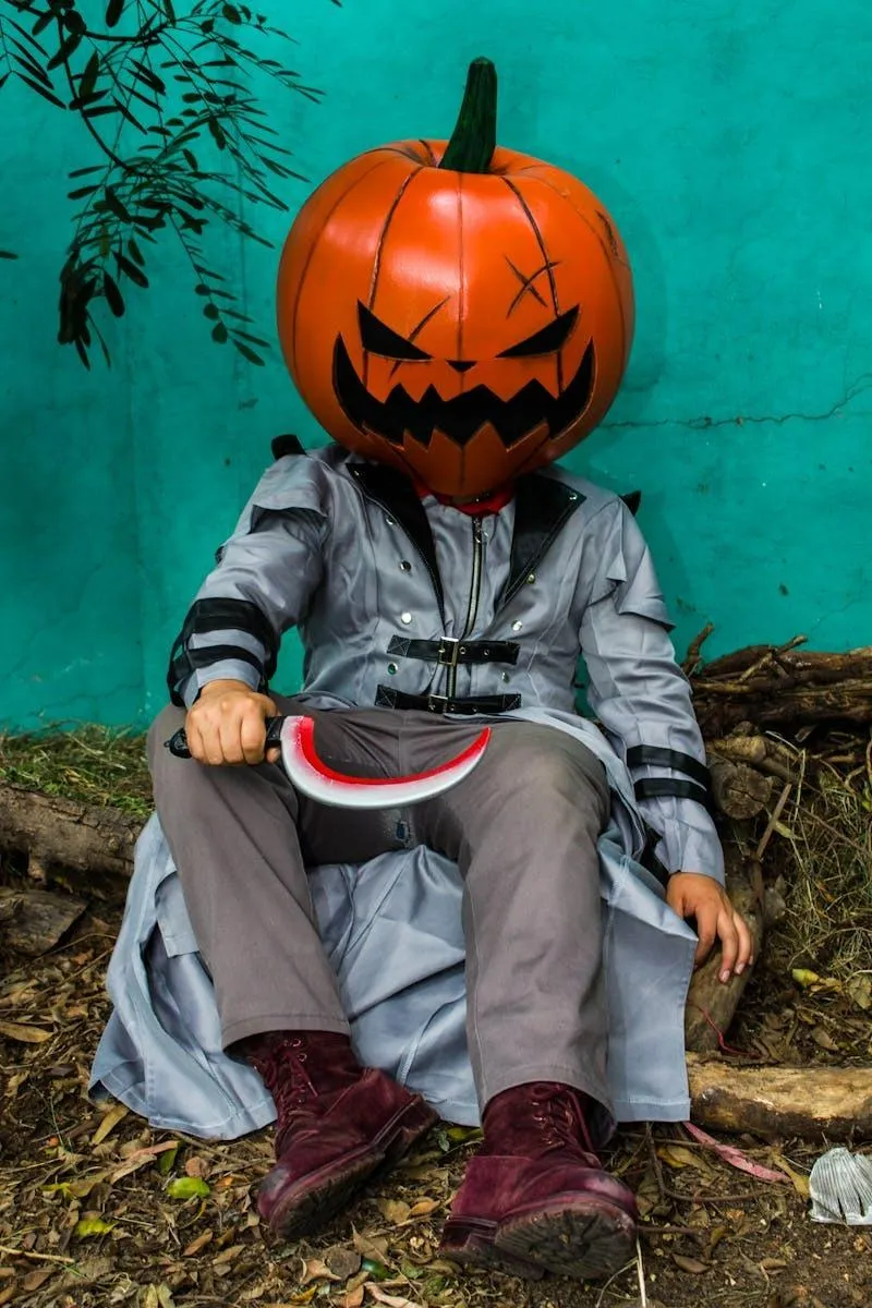 Child in Pumpkin Head Costume Sitting on Blue Background