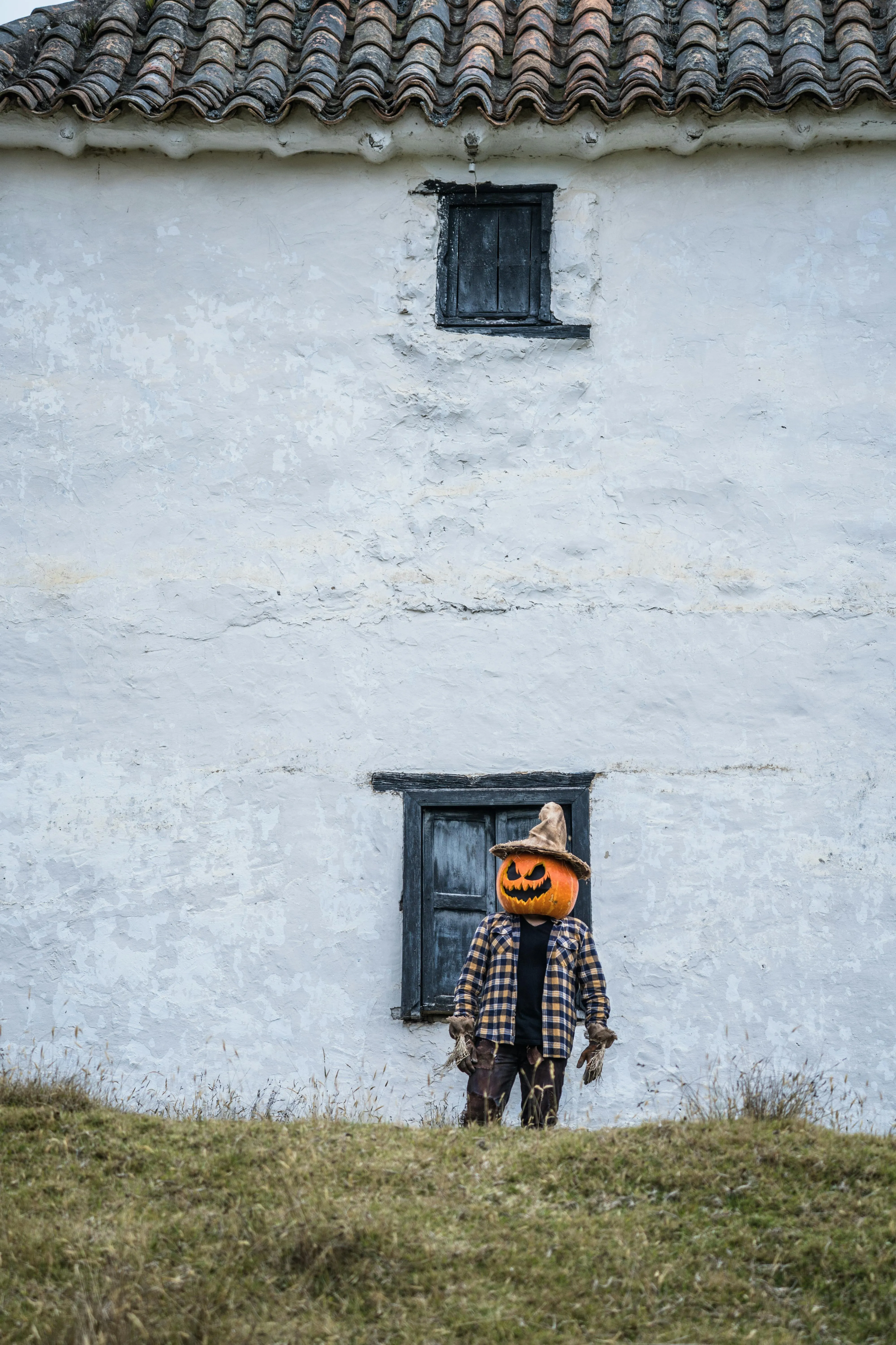 Child Wearing Pumpkin Head Costume Near White Building
