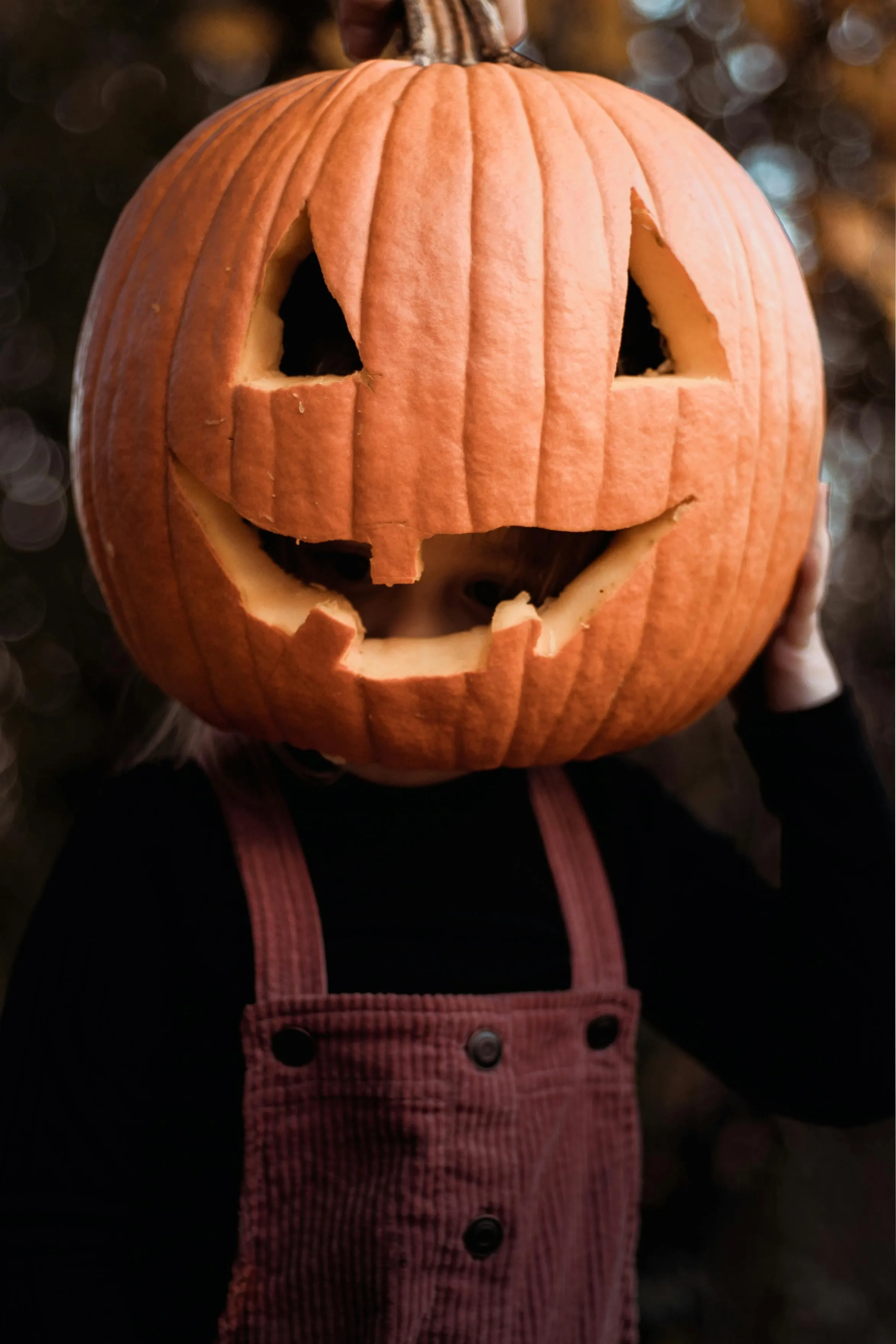 Close Up of Carved Pumpkin on Person Wearing Black Outfit