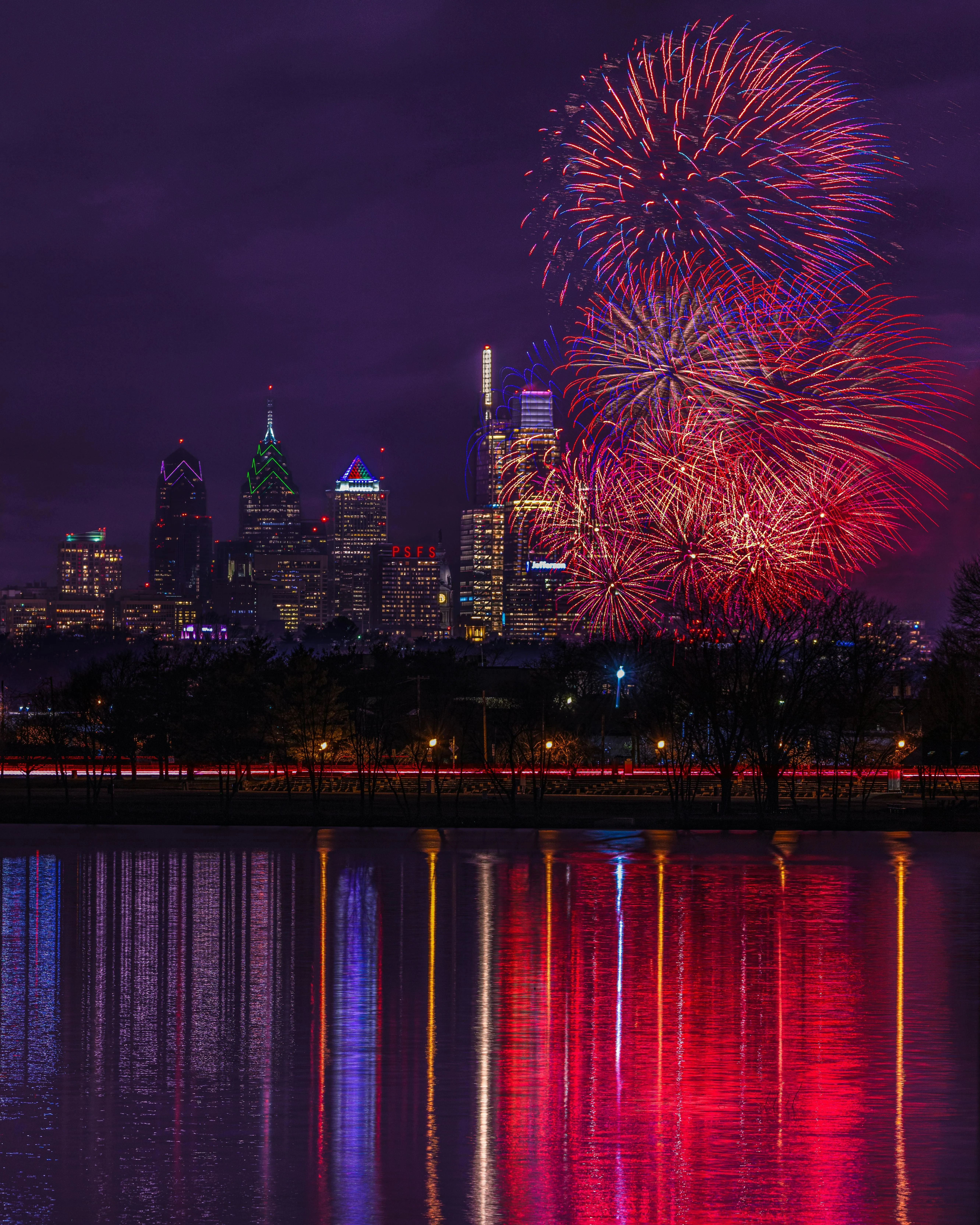 Colorful Fireworks above a City and Reflecting on Water