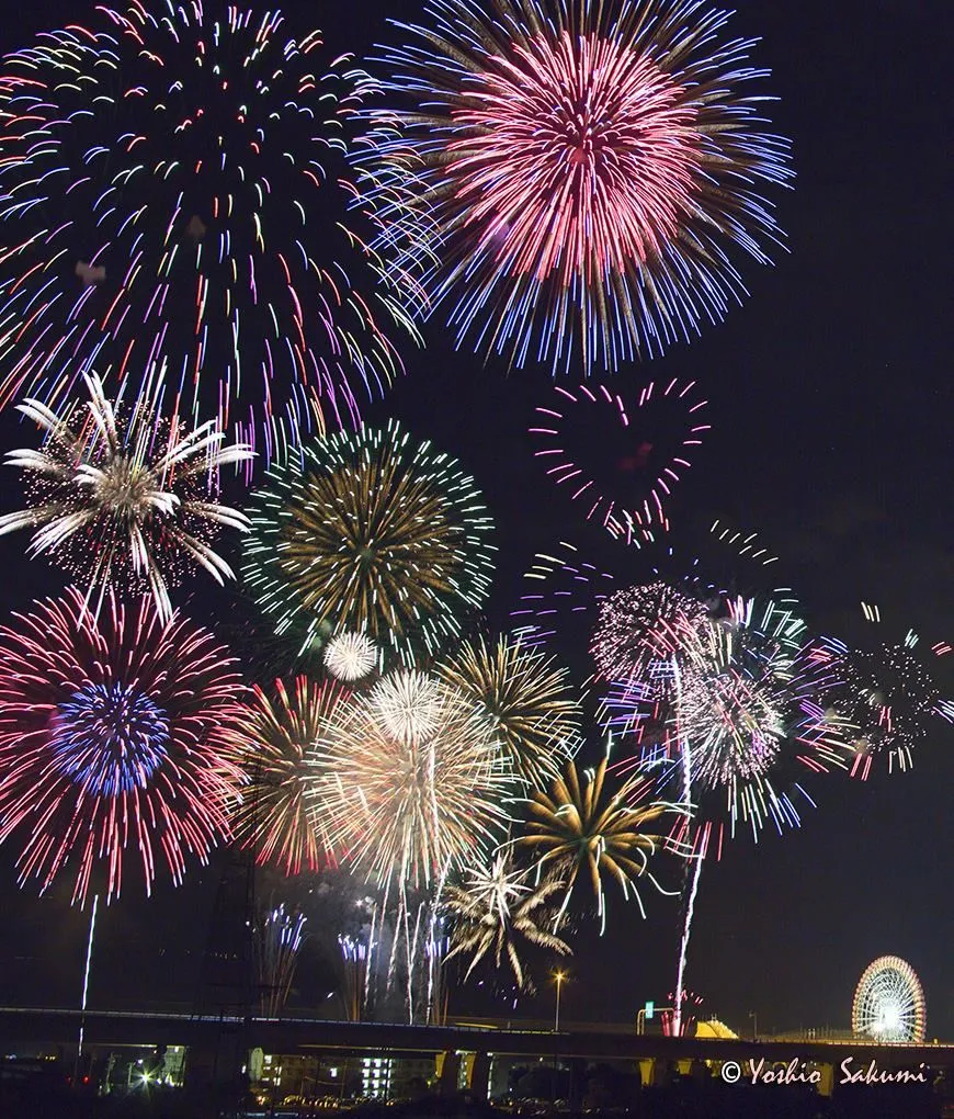 Colorful fireworks exploding against a dark cityscape at night