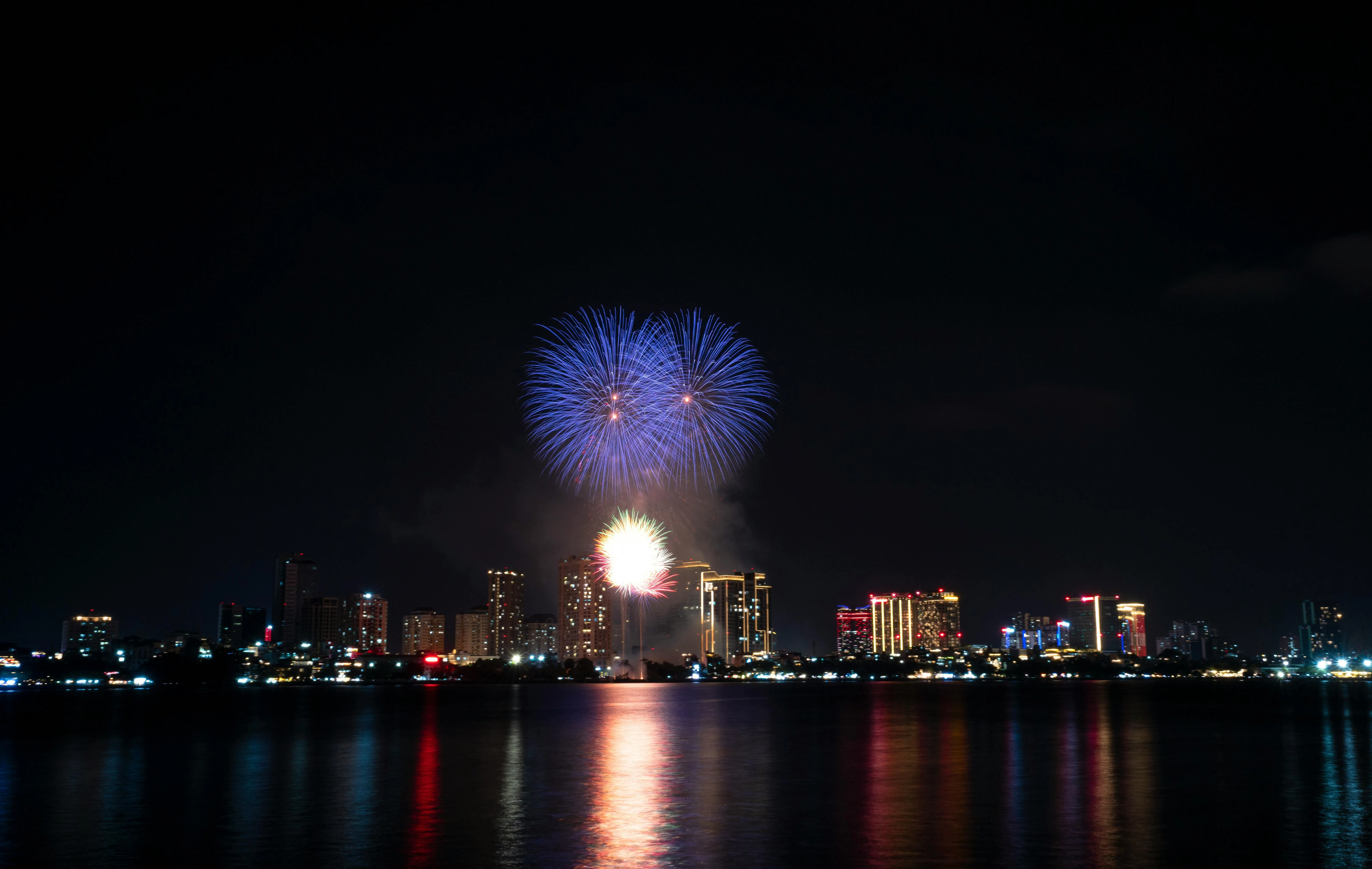 Colorful Fireworks over City with Reflections on Water