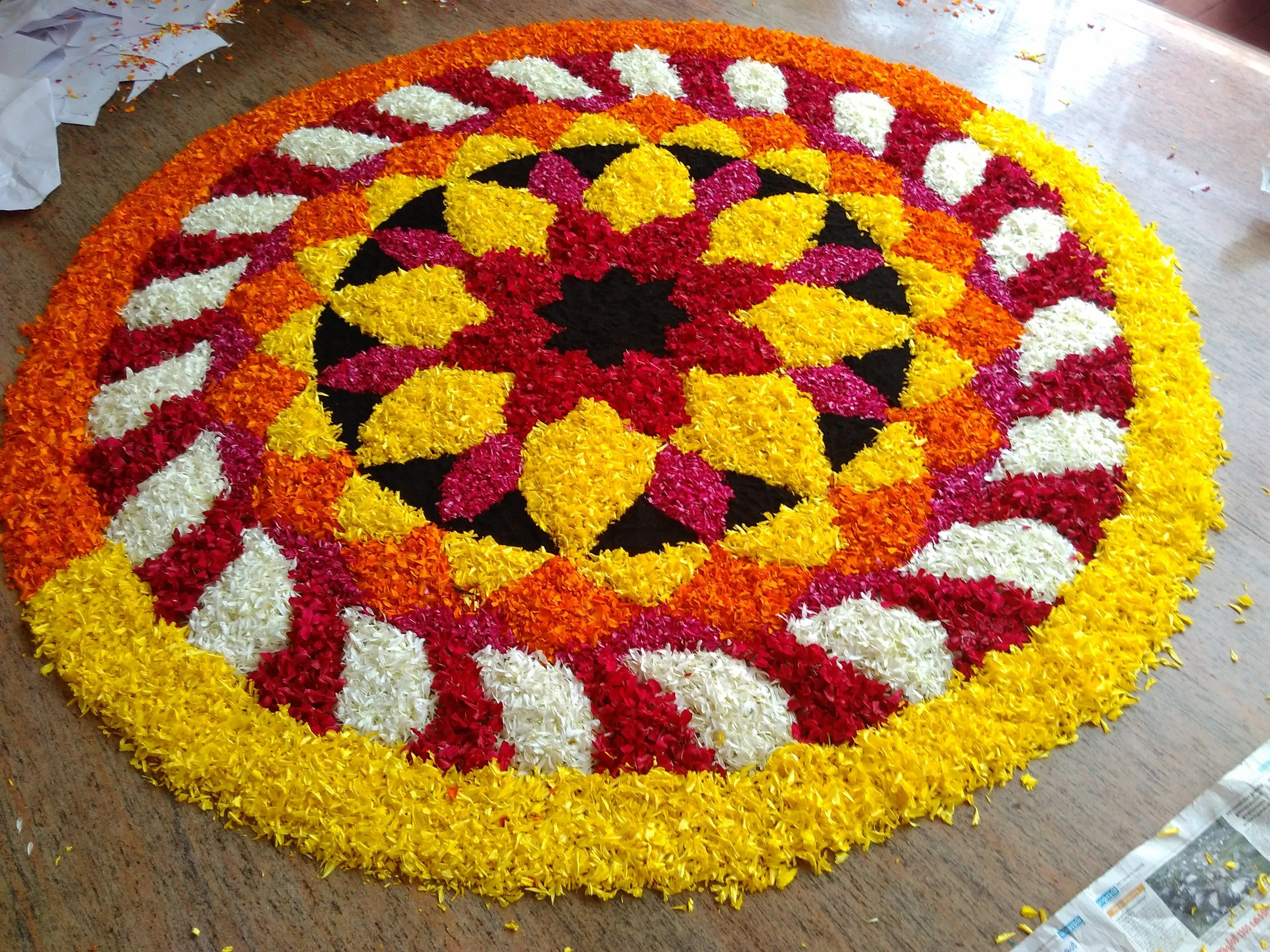 Colourful circular floral onam kolam with black center image