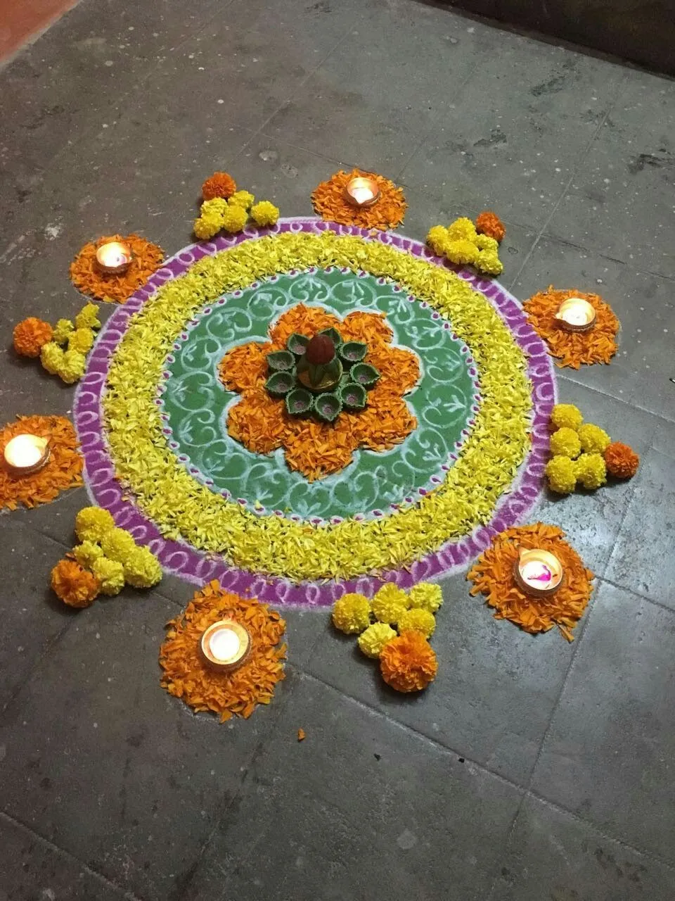 Colourful circular floral pookolam with Marigold and Lamps
