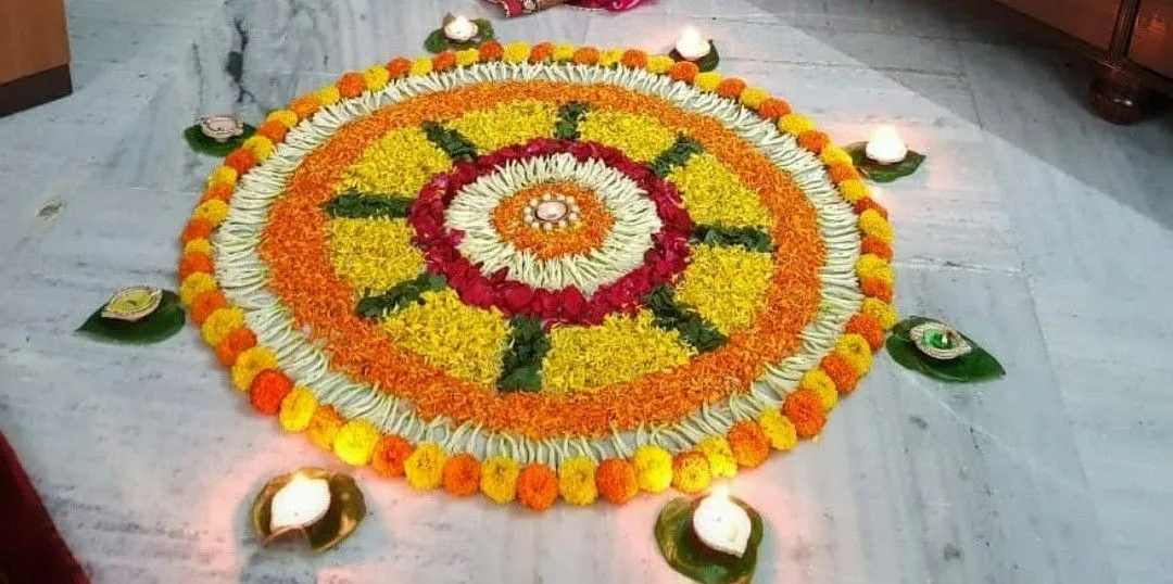 Colourful circular pookolam with marigold flowers and leaves