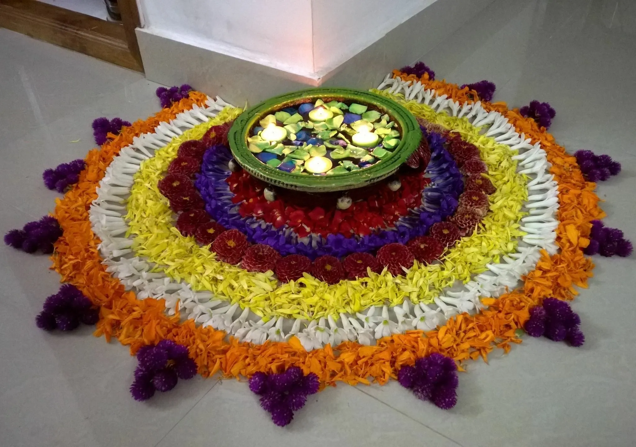 Corner pookolam design with a floating lamp centerpiece