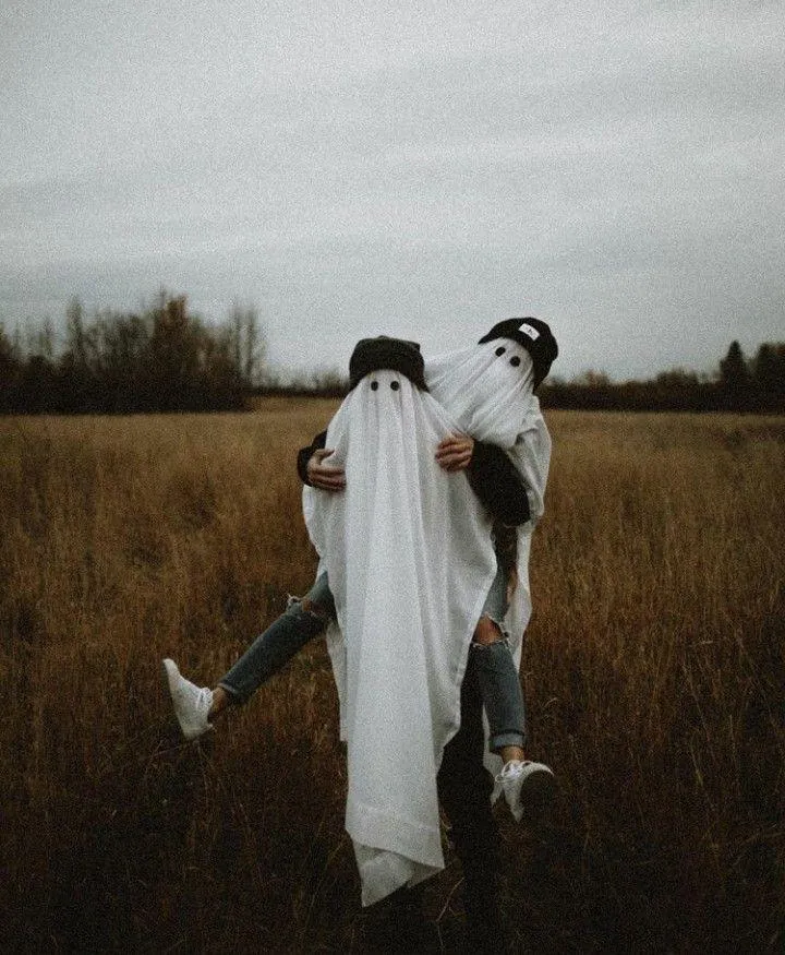 Couple Dressed as Ghosts with Pumpkin Heads in Field image