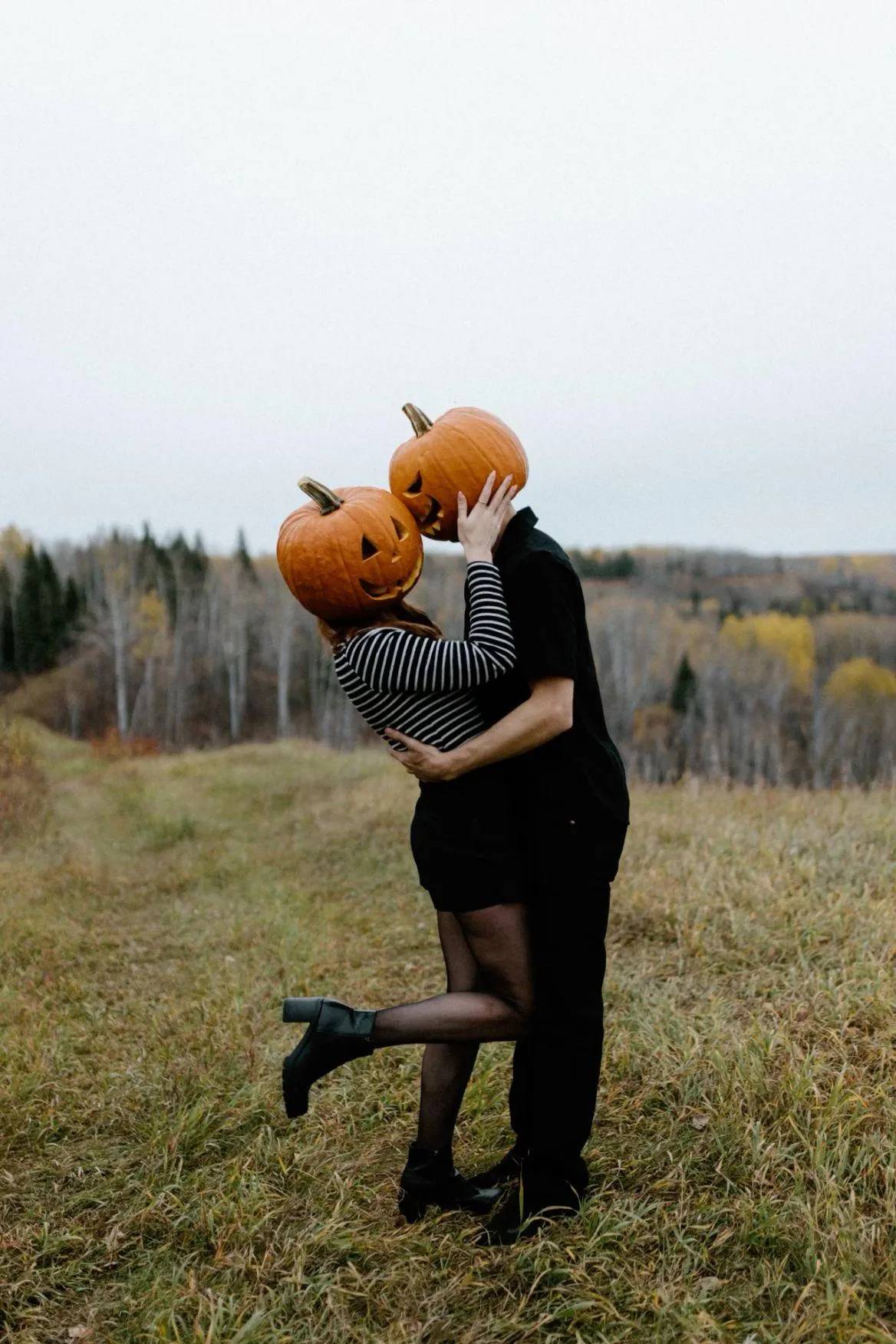Couple Embracing with Pumpkin Masks in Autumn Landscape