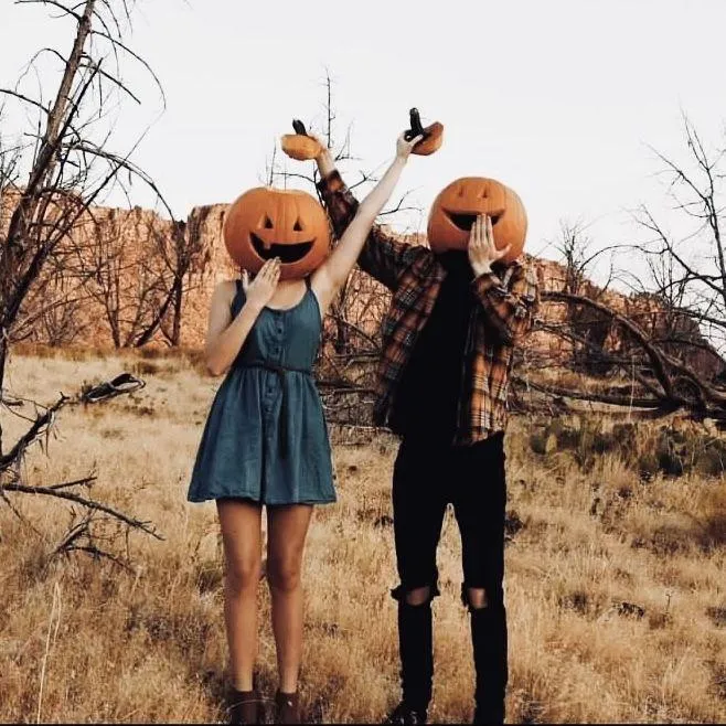 Couple Holding Pumpkin Heads in Autumn Landscape image