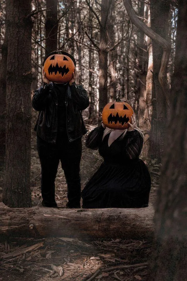 Couple in black Wearing Pumpkin Head Masks in Forest