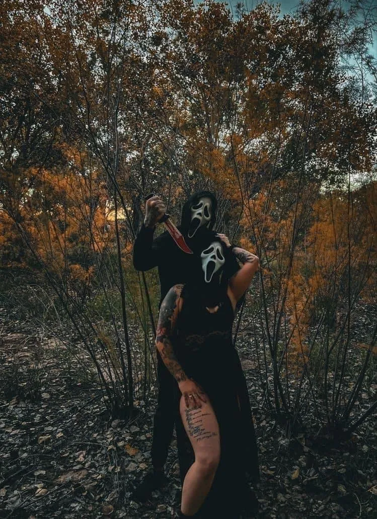 Couple in Ghostface Masks Poses with Knife in Spooky Forest