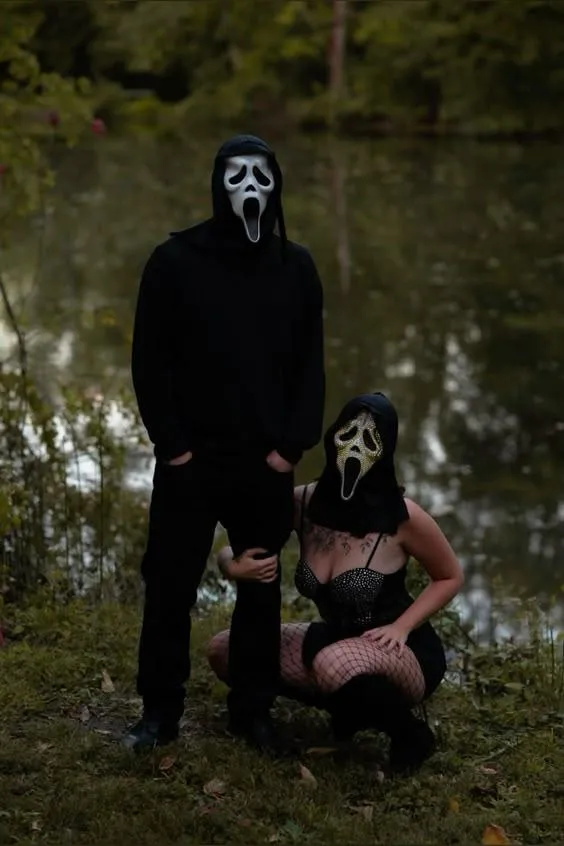 Couple in Halloween costumes with masks and pumpkin heads