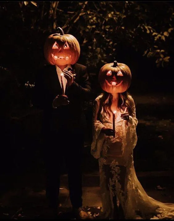 Couple in Pumpkin Head Costumes Dark Shadowy Background