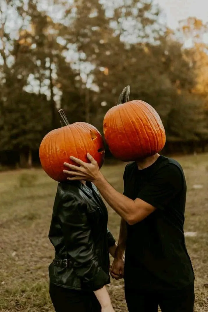 Couple in Pumpkin Head Costumes Sharing a Halloween Moment