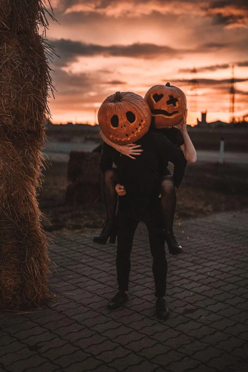 Couple in Pumpkin Head Masks and posing at Sunset Outdoor