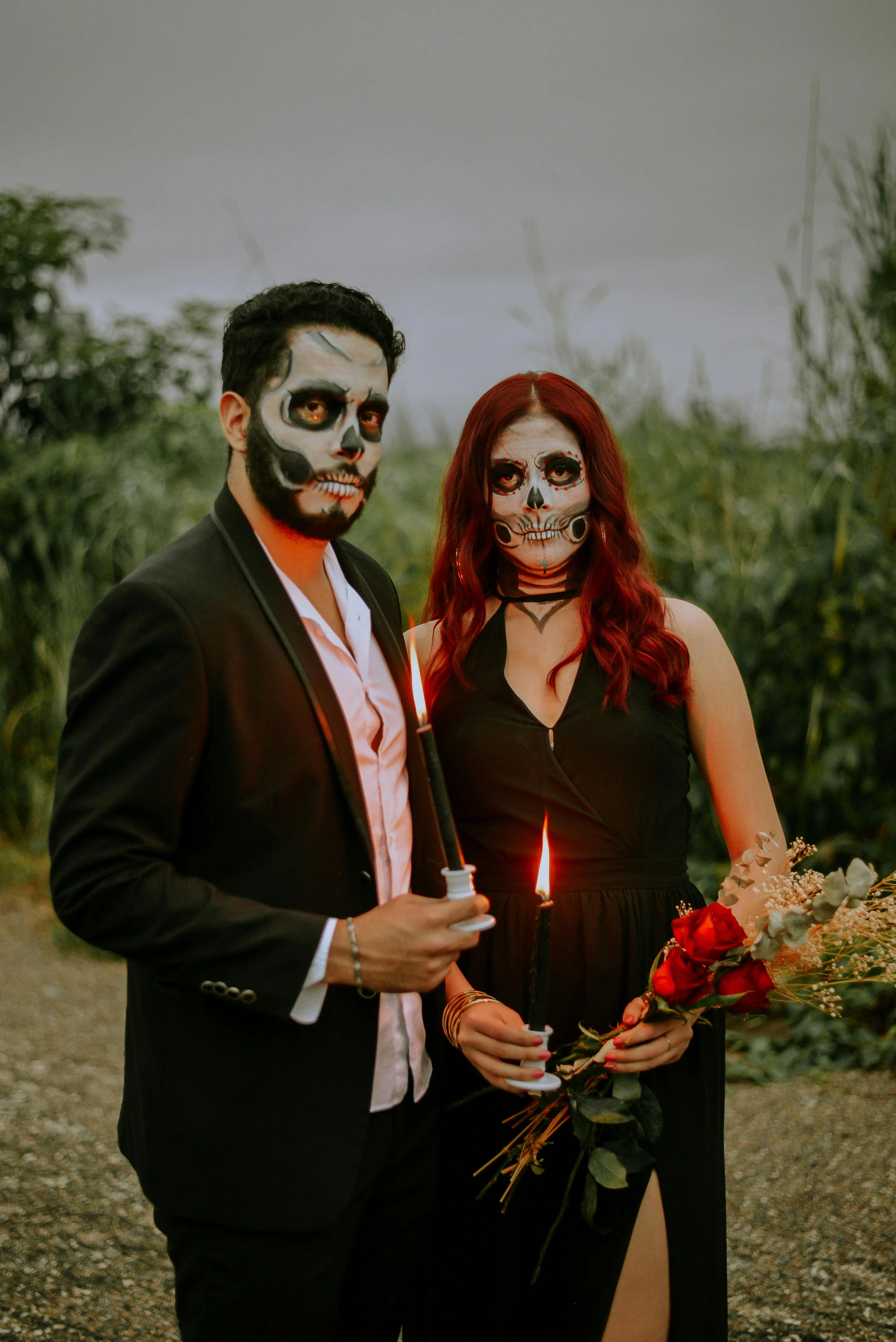 Couple in Skull Makeup and Formal Wear Holding Flowers