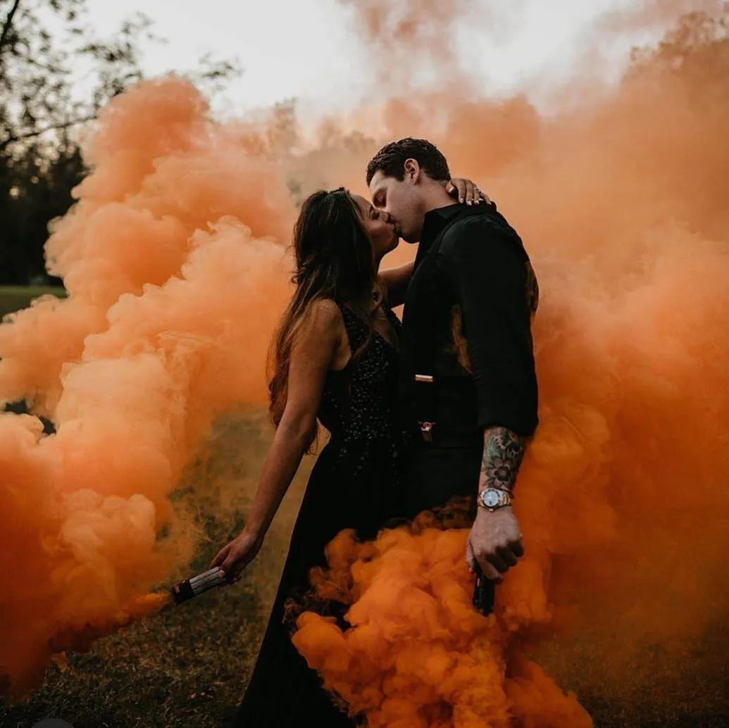 Couple kissing on a forest surrounded with orange smoke