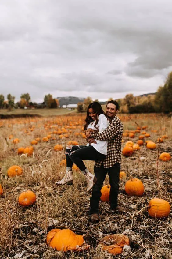 Couple Posing in Pumpkin Patch on Cloudy Halloween Day