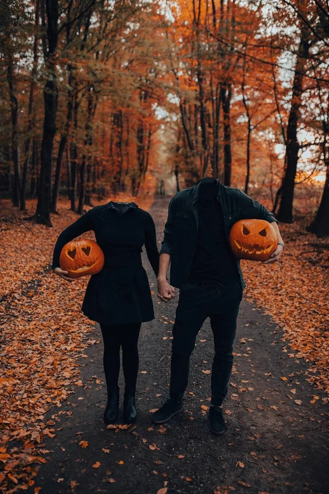 Couple Walking Holding Pumpkin Heads on Forest Path