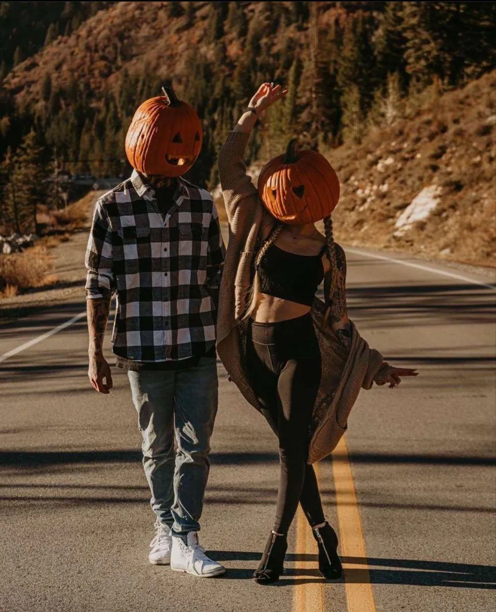 Couple Walking with Pumpkin Heads on a Fall Road Wallpaper