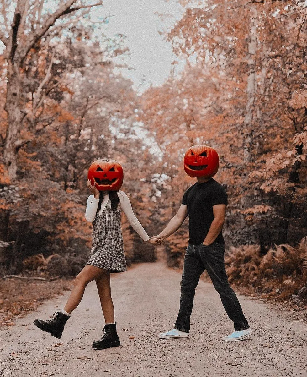 Couple Walking with Pumpkin Masks on Autumn Trail image