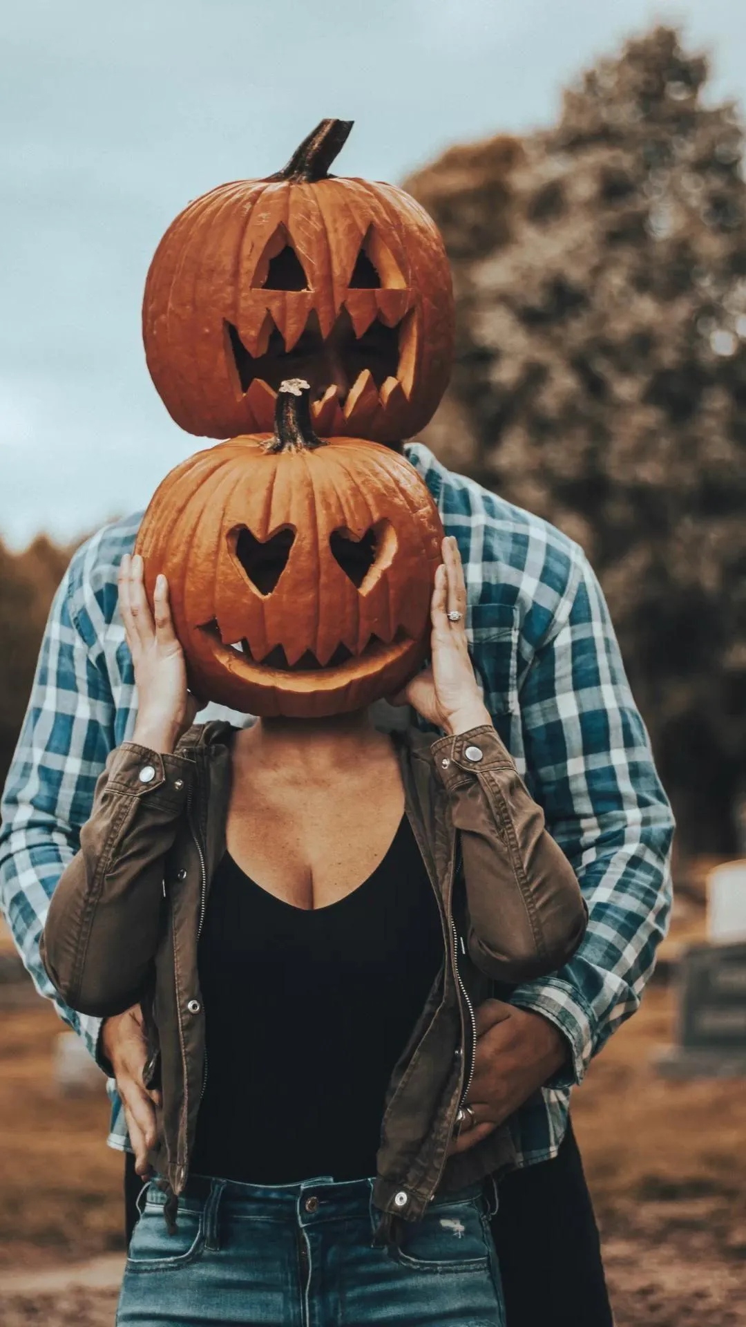 Couple Wearing Double Pumpkin Head Costumes Outdoors