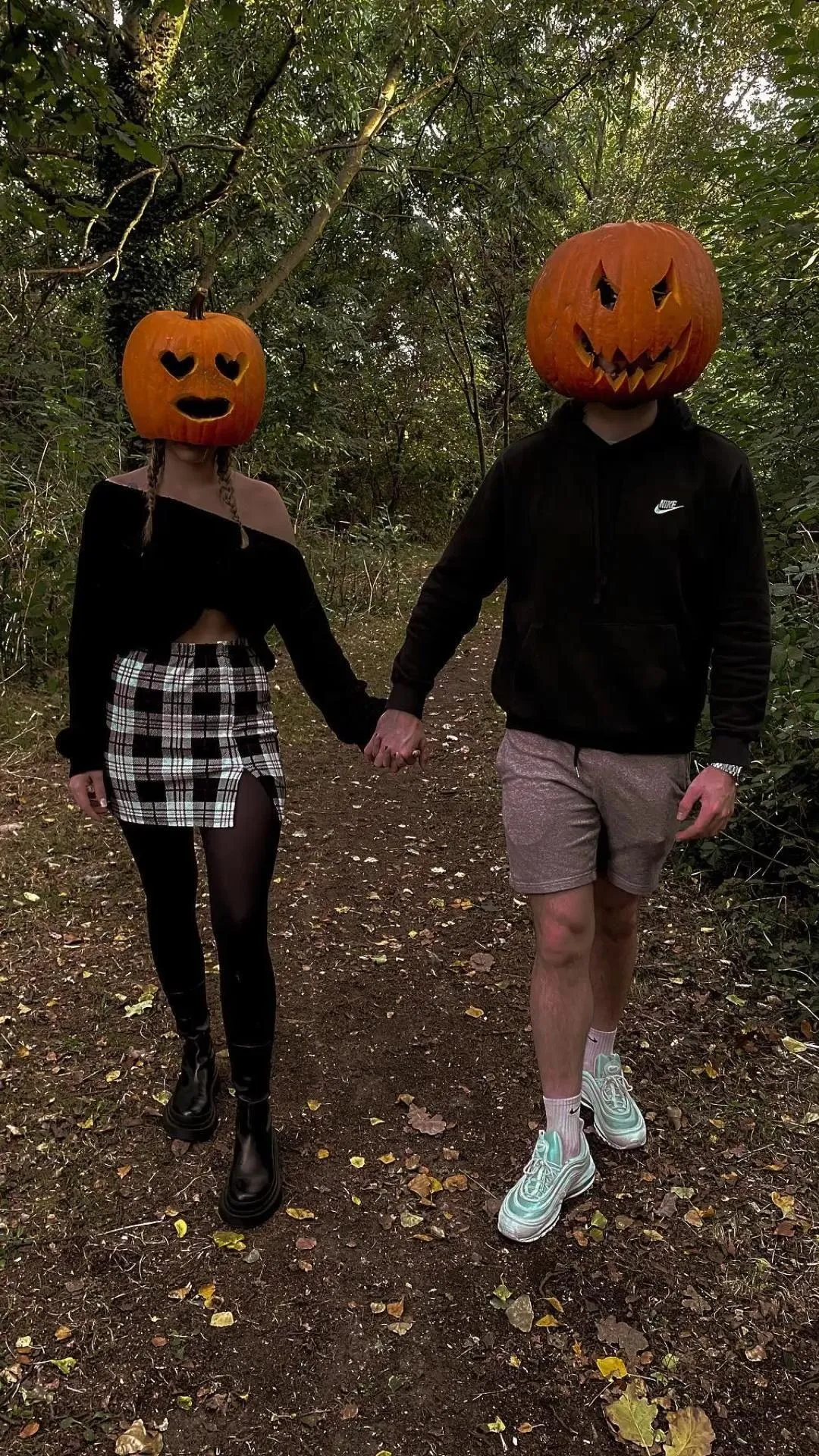 Couple Wearing Pumpkin Heads Walking in Autumn Forest