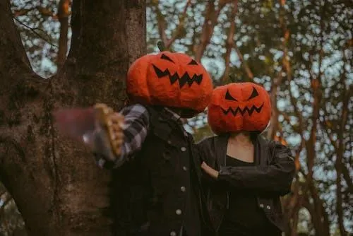 Couples in Pumpkin Head Costumes with Halloween Atmosphere