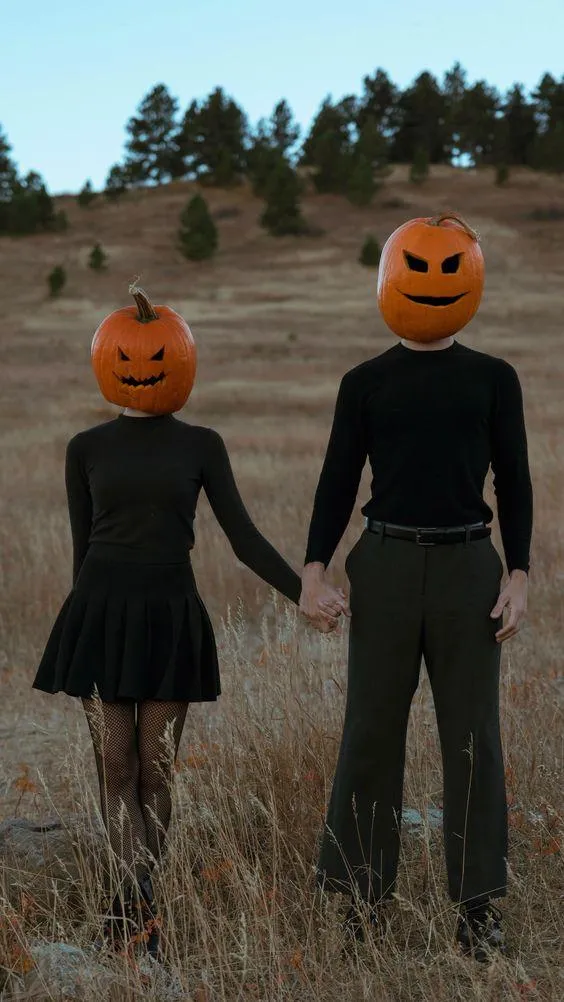 Couples Wearing Pumpkin Heads Holding Hands in Field