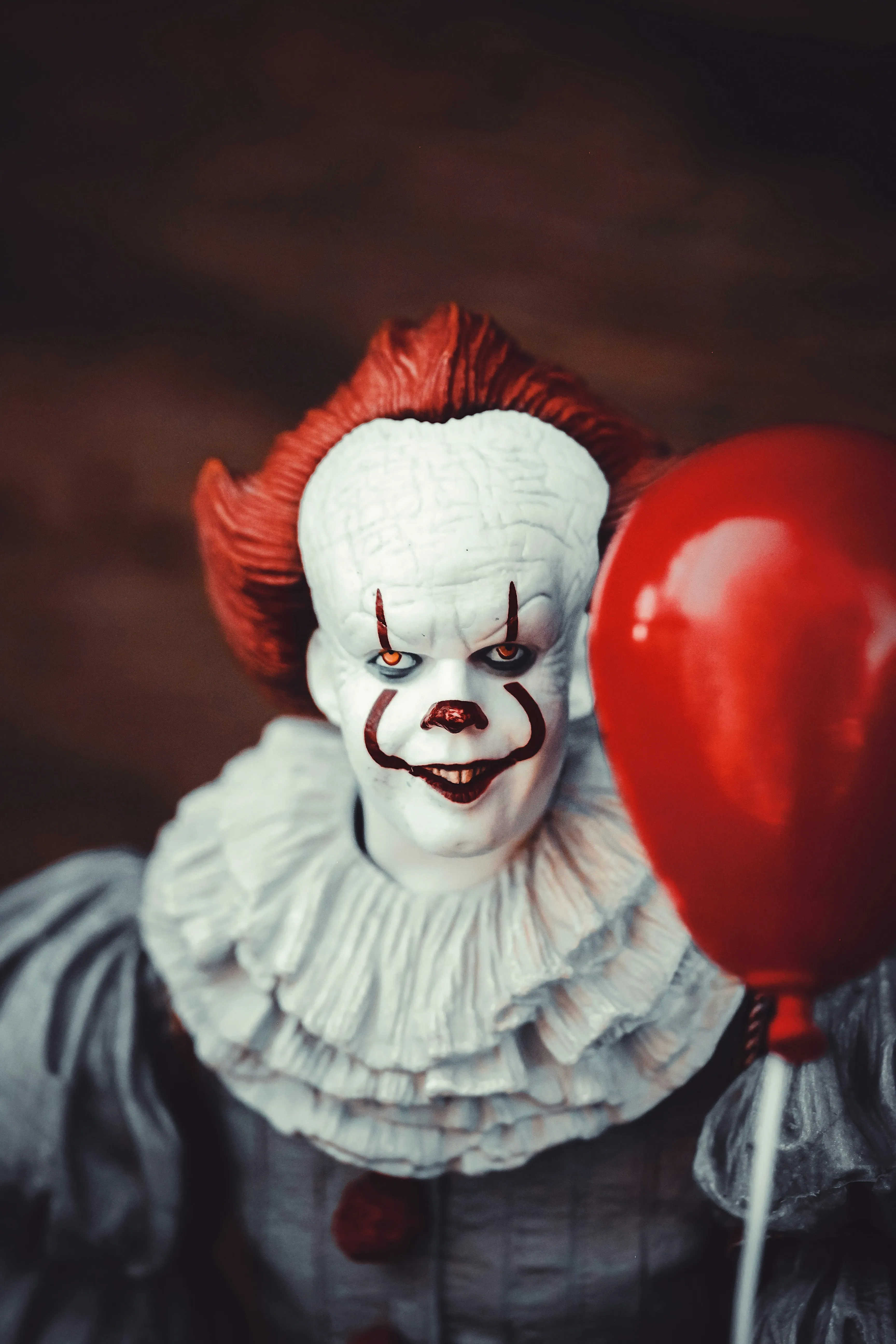 Creepy Clown with Red Balloon in Dark Setting Wallpaper