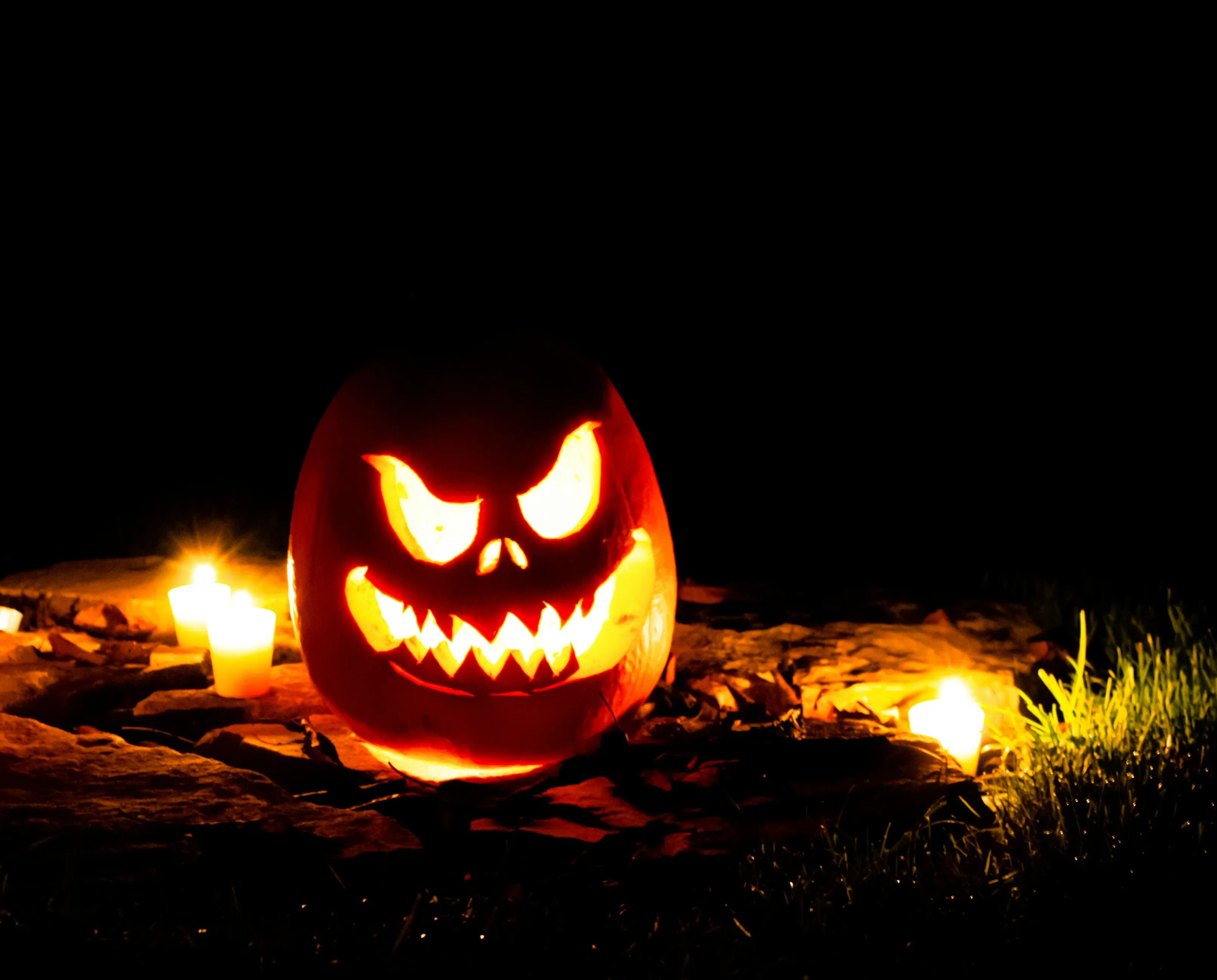Creepy Jack O Lantern Illuminated at Night on Grass Image