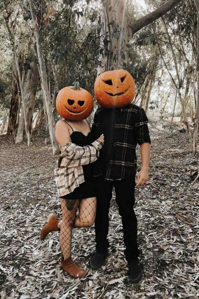 Cute Couple in Pumpkin Heads Embracing in Woods image