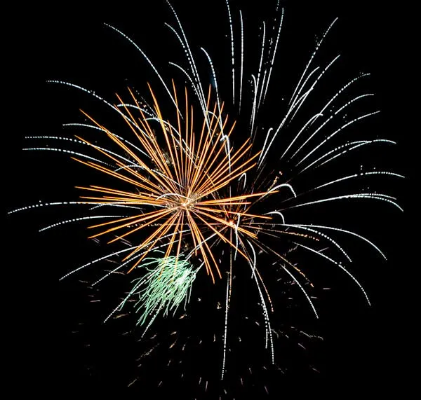 Dynamic Firework Display with Orange and Green Trails