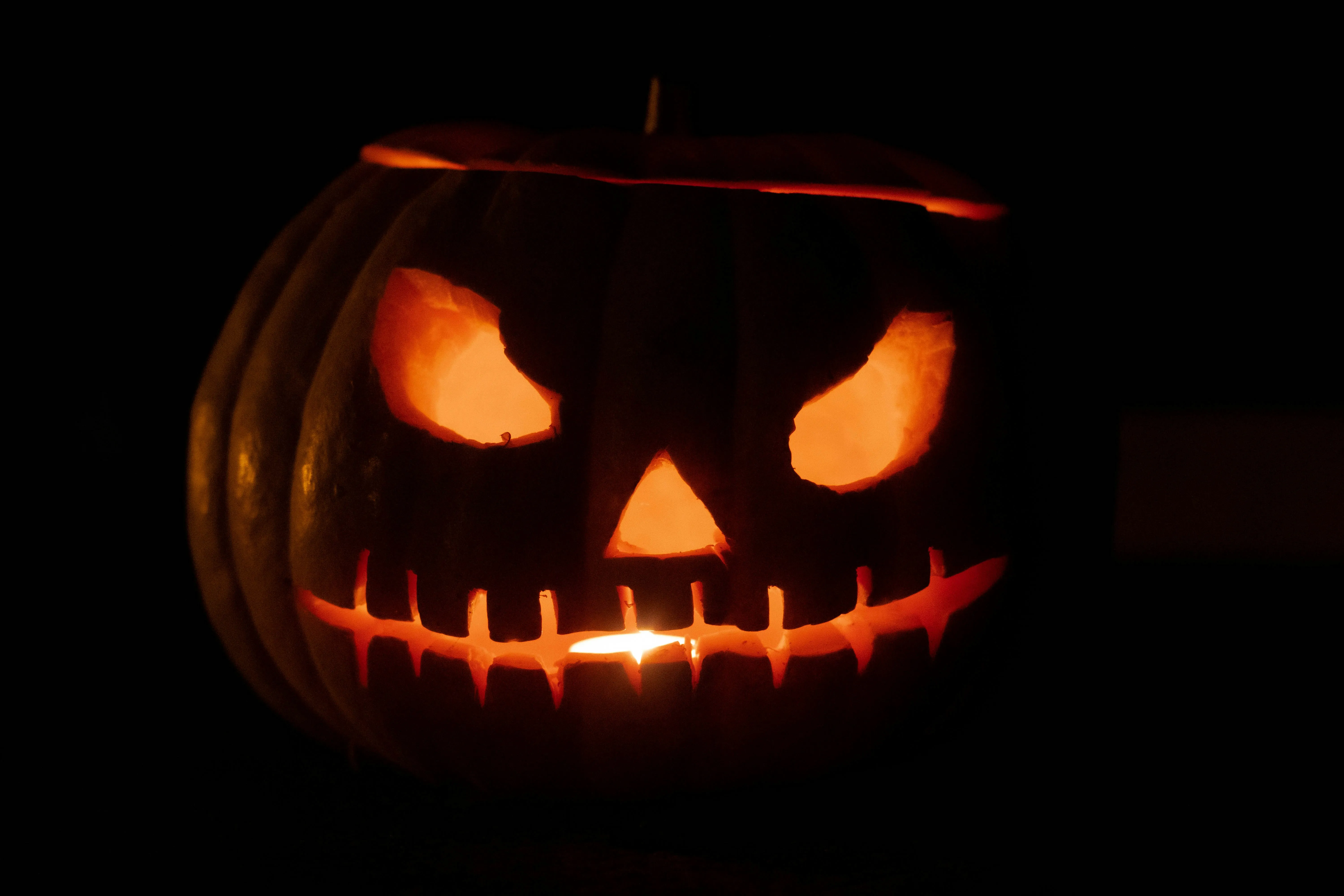 Eerie Carved Pumpkin with Stitched Mouth at Night Wallpaper