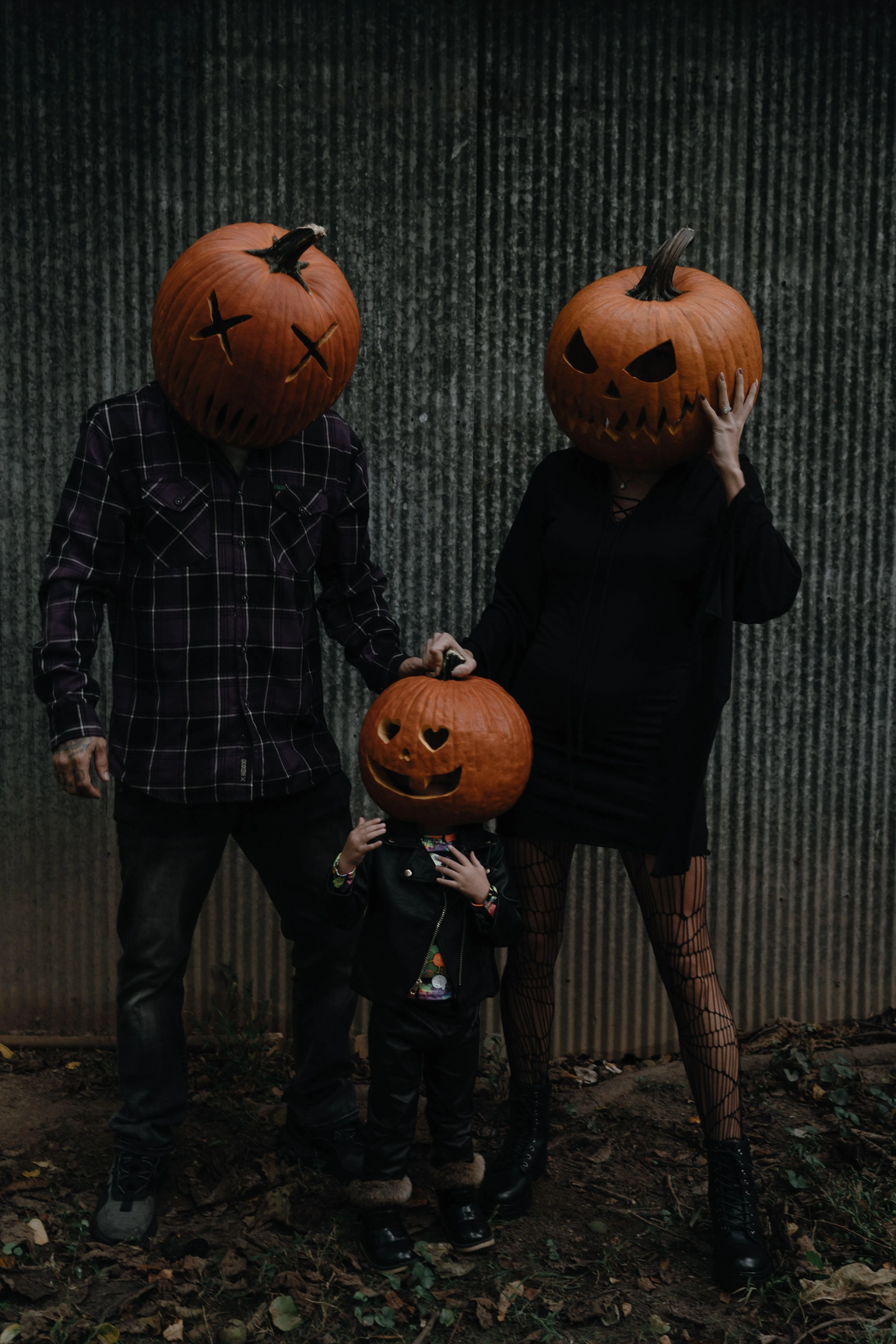 Family Wearing Pumpkin Head Costumes in Dark Setting