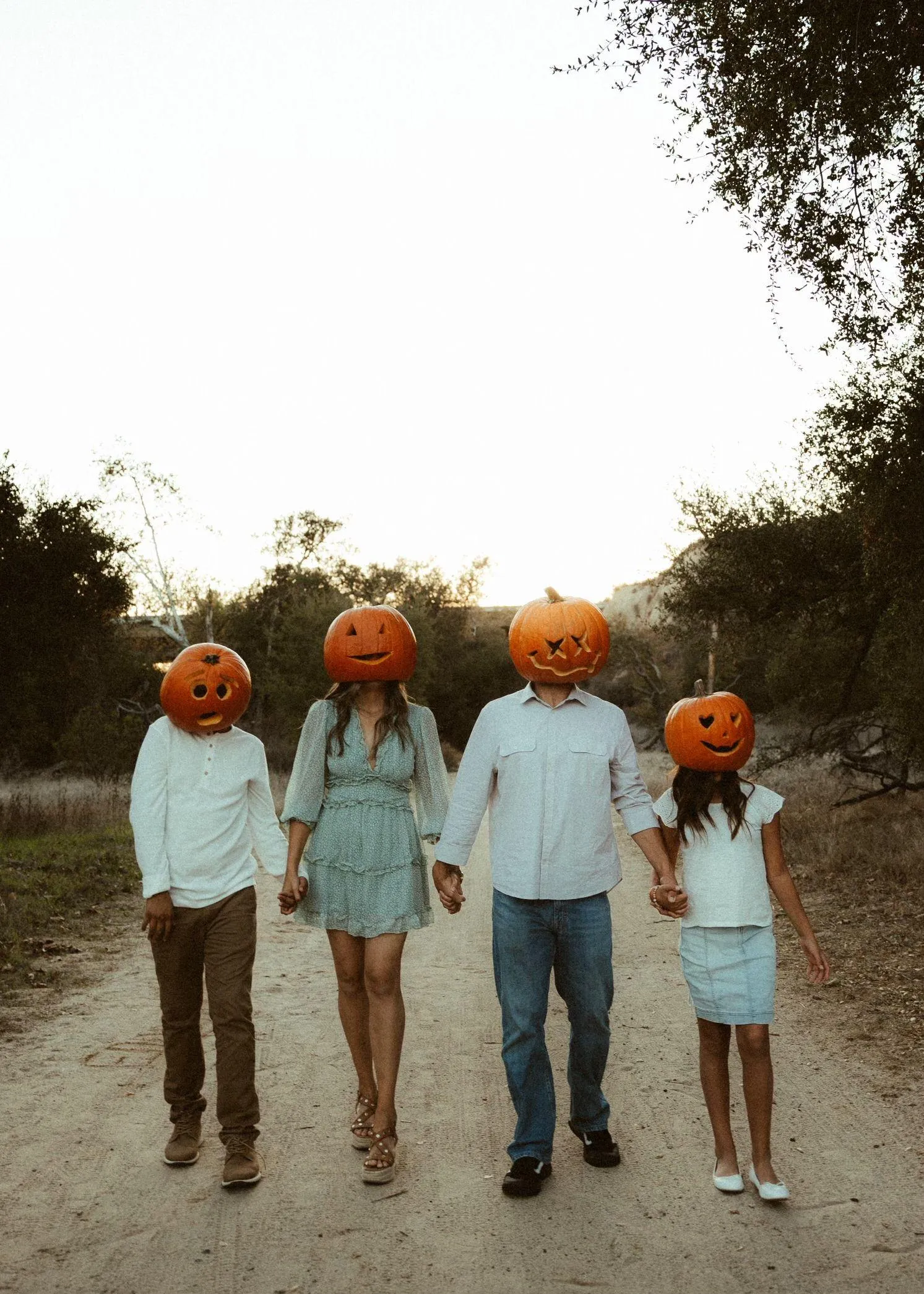 Family Wearing Pumpkin Heads on Rural Road for Halloween