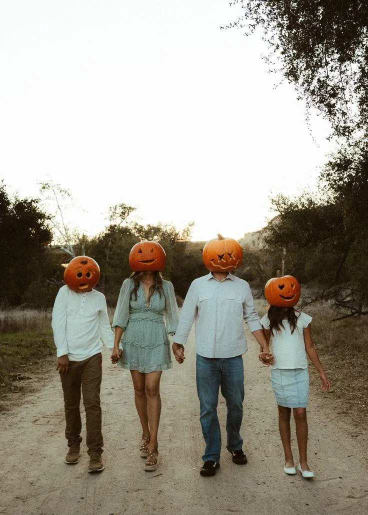 Family Wearing Pumpkin Heads Walking in Autumn Forest