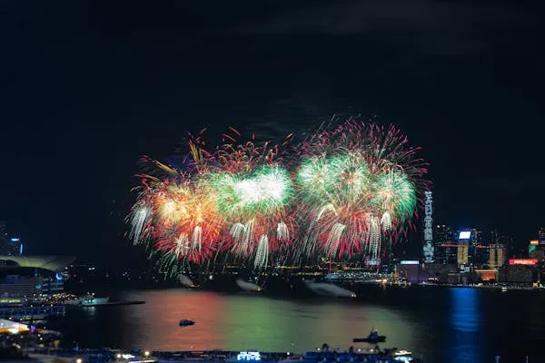 Firework Display over Water with City Lights in Background