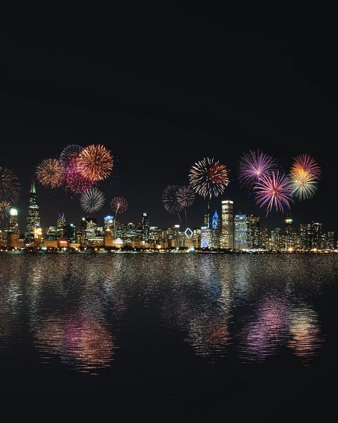 Fireworks above a cityscape with reflections on the water