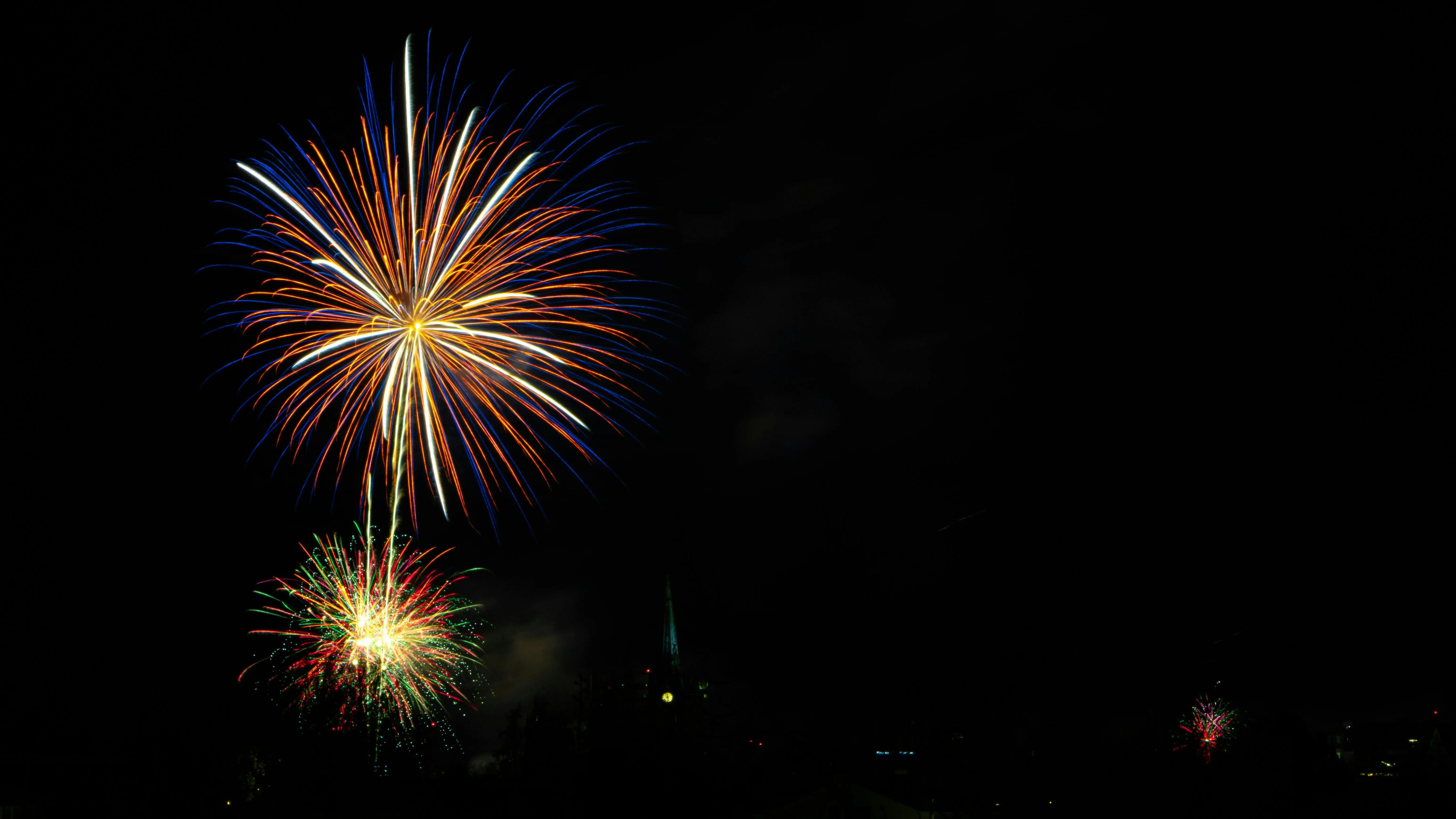 Fireworks bursting in various colors in the dark sky