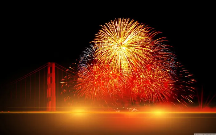 Fireworks bursting over a city with bright colors Wallpaper