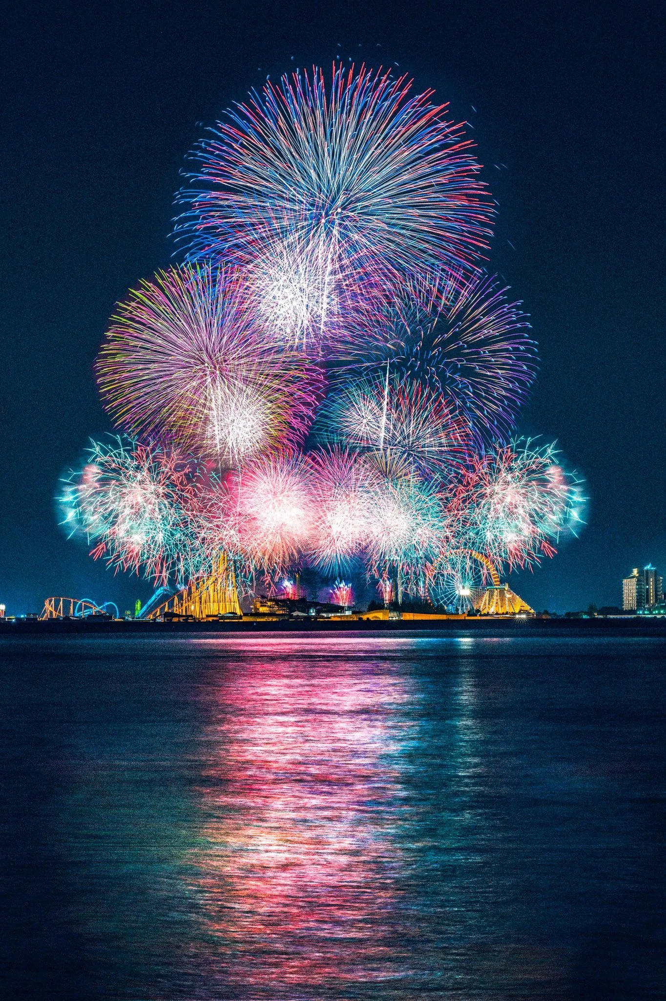 Fireworks exploding above the calm water surface at night