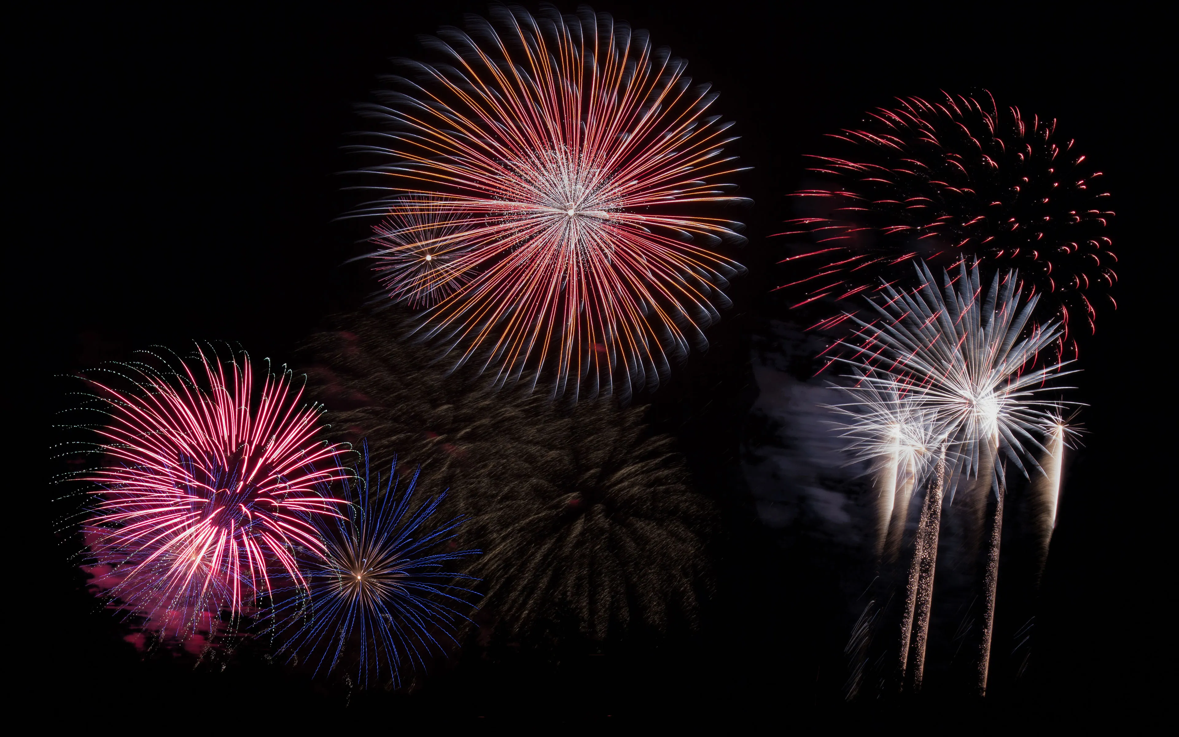 Fireworks exploding over the ocean with a dark sky