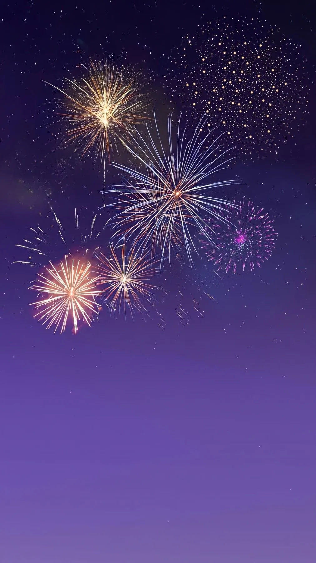 Fireworks in purple sky with small bursts of soft colors