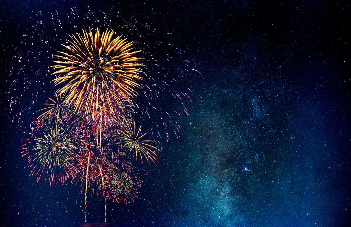 Fireworks shine in deep night sky with glowing sparkles