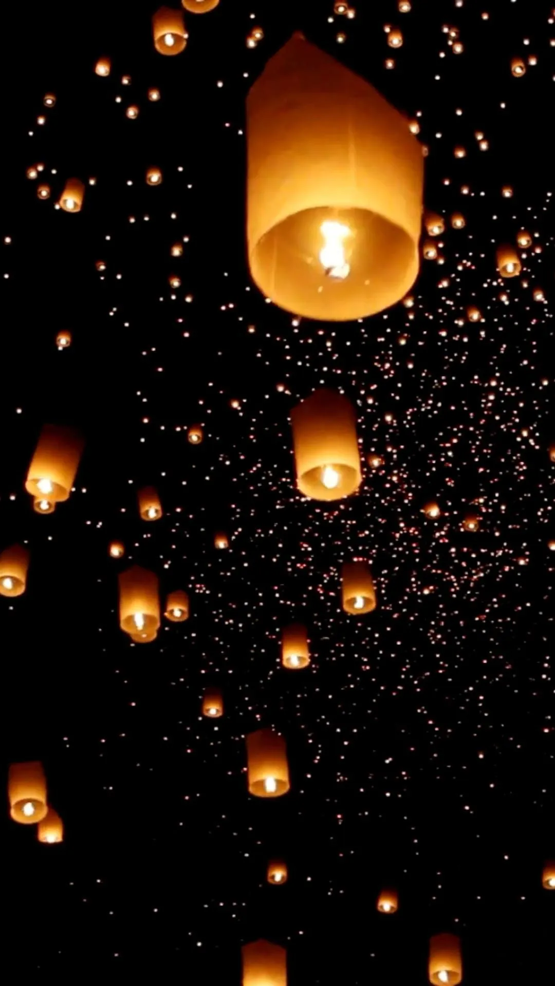 Floating lanterns glowing against a starry night sky