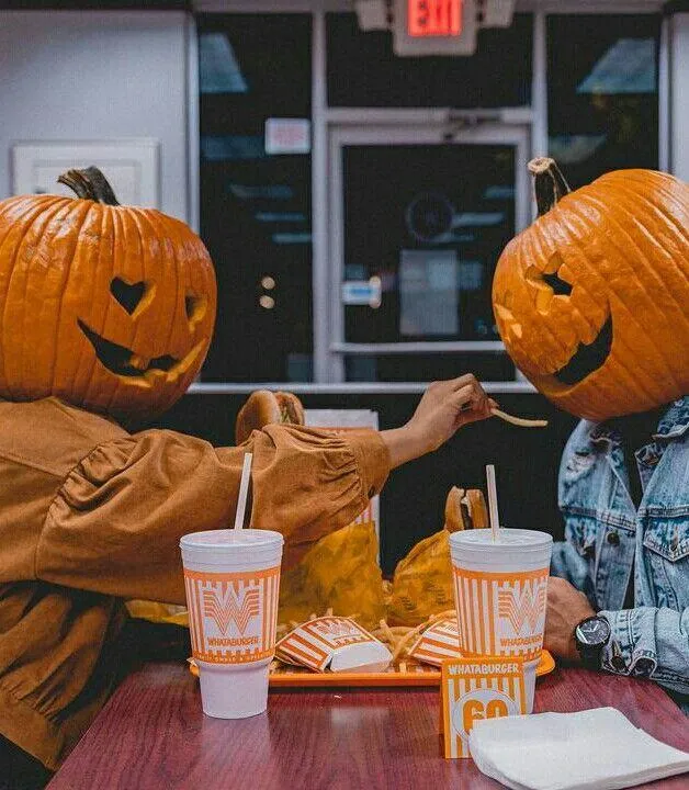 Friends Sharing Drinks Wearing Pumpkin Head Costumes Image