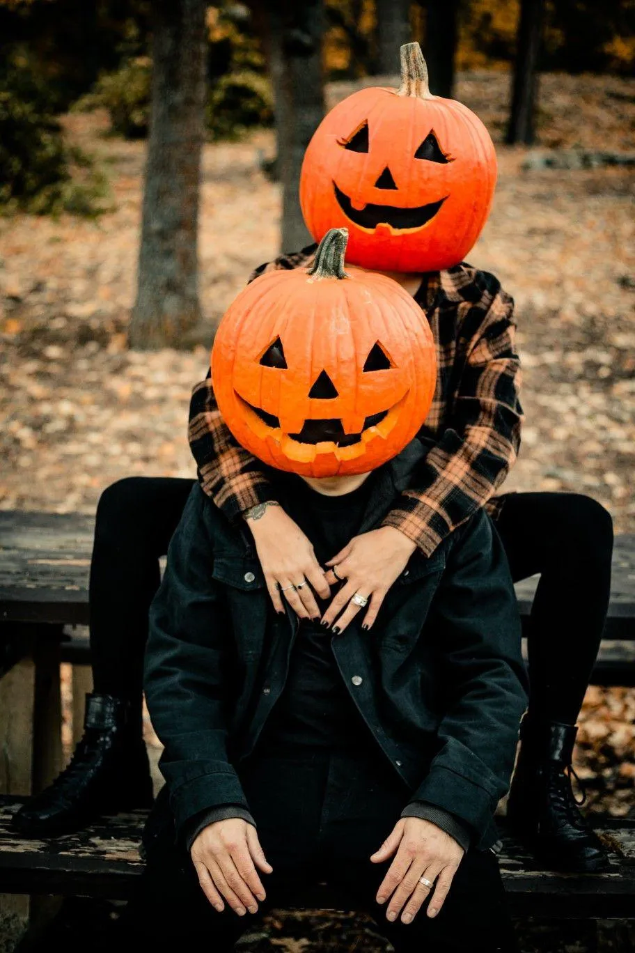 Friends Sitting in Pumpkin Heads on Bench and posing